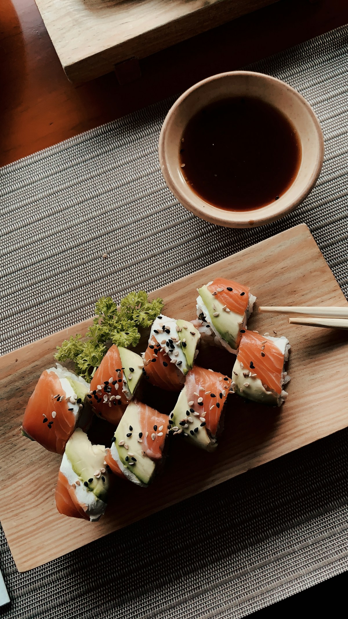 Salmon and avocado rolls on a wooden board with soy sauce
